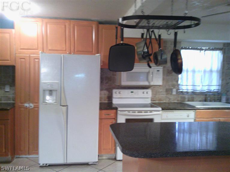 504 Penn Road West Lehigh Acres, FL 33936 - Photo 6 of 7 a kitchen with a stove and a refrigerator