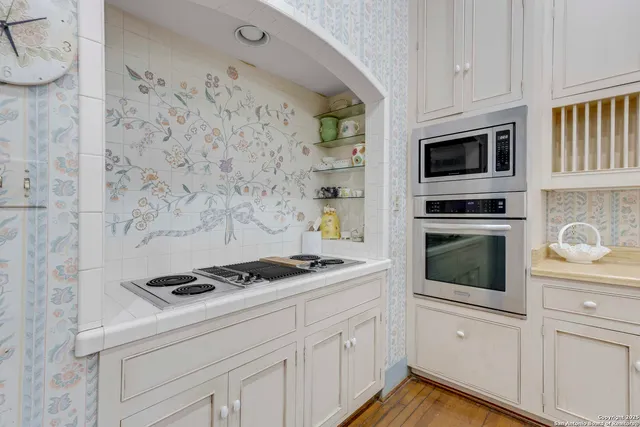 a kitchen with white cabinets stainless steel appliances and wooden floor