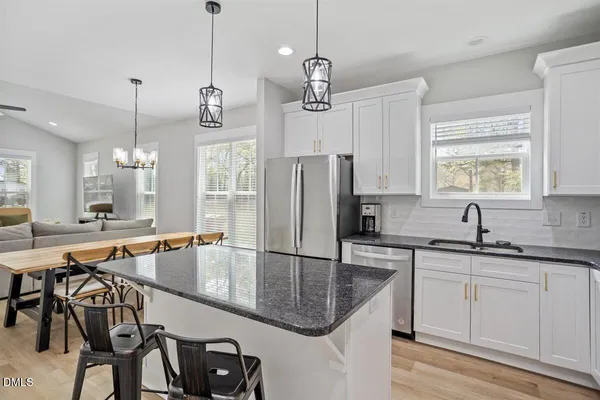 a kitchen with granite countertop a sink a counter space appliances and cabinets