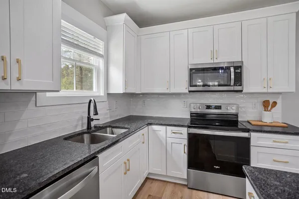 a kitchen with granite countertop white cabinets and stainless steel appliances