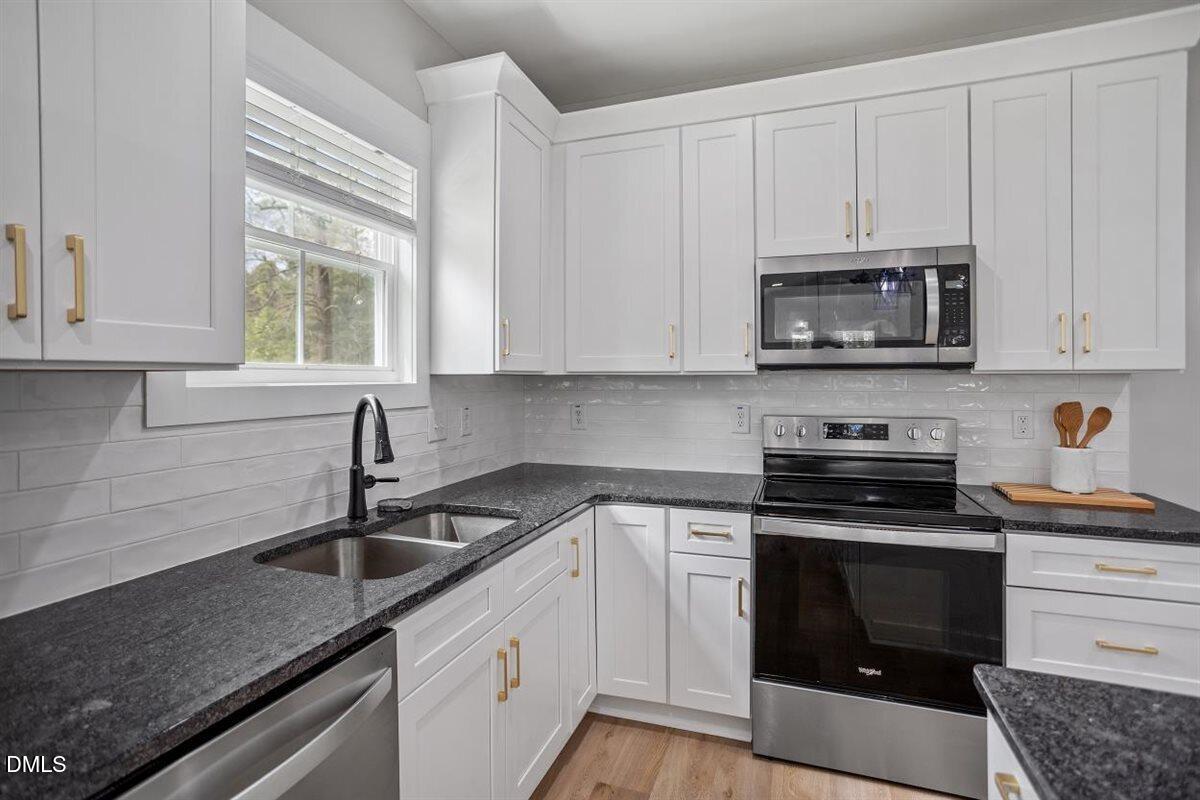 506 Dogwood Road Holly Springs, NC 27540 - Photo 16 of 42 a kitchen with granite countertop white cabinets and stainless steel appliances