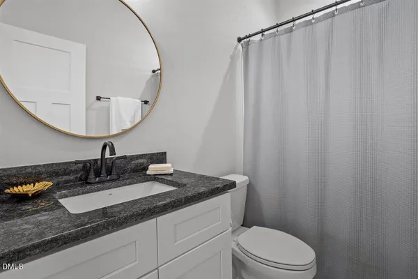 a bathroom with a granite countertop sink vanity mirror and toilet