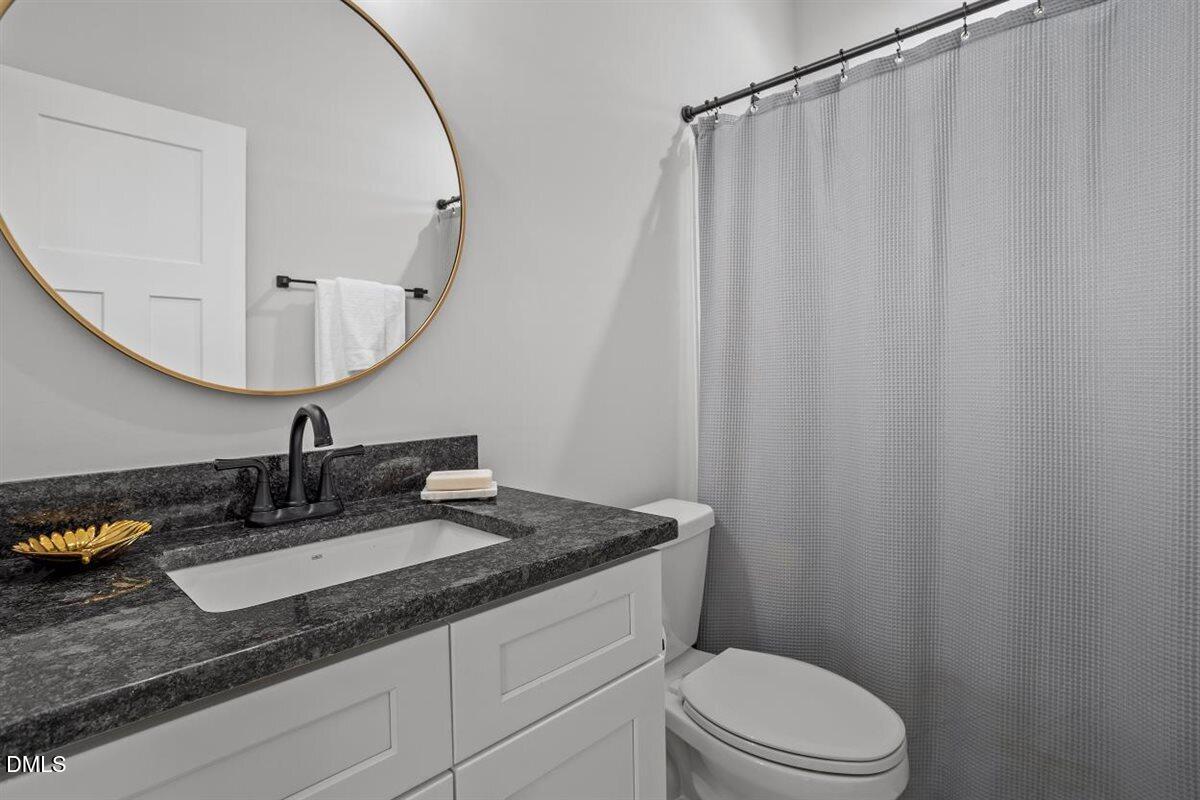 506 Dogwood Road Holly Springs, NC 27540 - Photo 31 of 42 a bathroom with a granite countertop sink vanity mirror and toilet