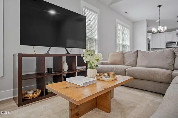 a living room with furniture a flat screen tv and floor to ceiling window