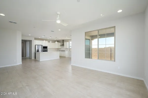 a view of an empty room with kitchen and window