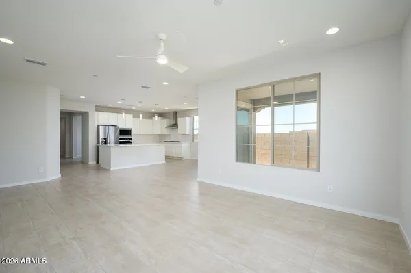 a view of an empty room with kitchen and window