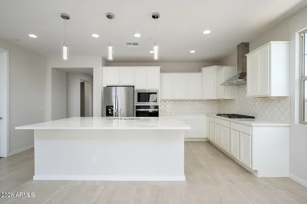 a large kitchen with stainless steel appliances a large counter top a stove a refrigerator a sink and a refrigerator