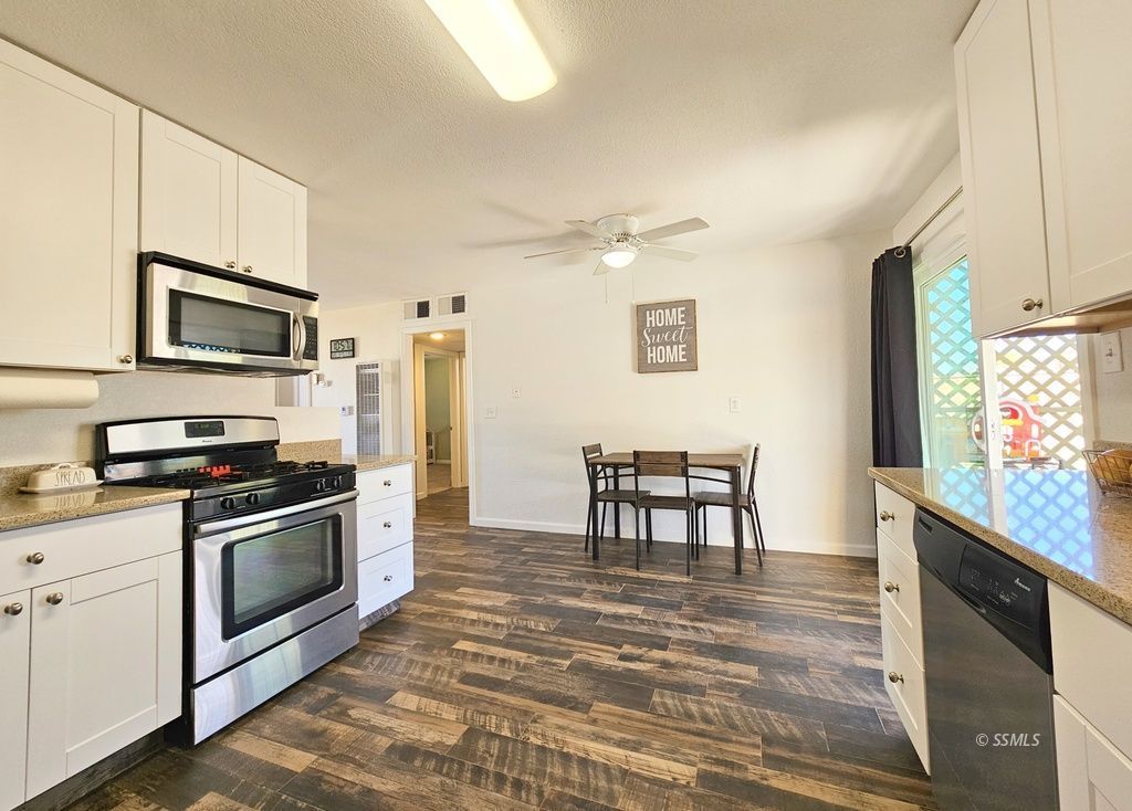 630 South Sunset Street Ridgecrest, CA 93555 - Photo 10 of 34 a kitchen with stainless steel appliances granite countertop a stove top oven a sink dishwasher a dining table and chairs with wooden floor