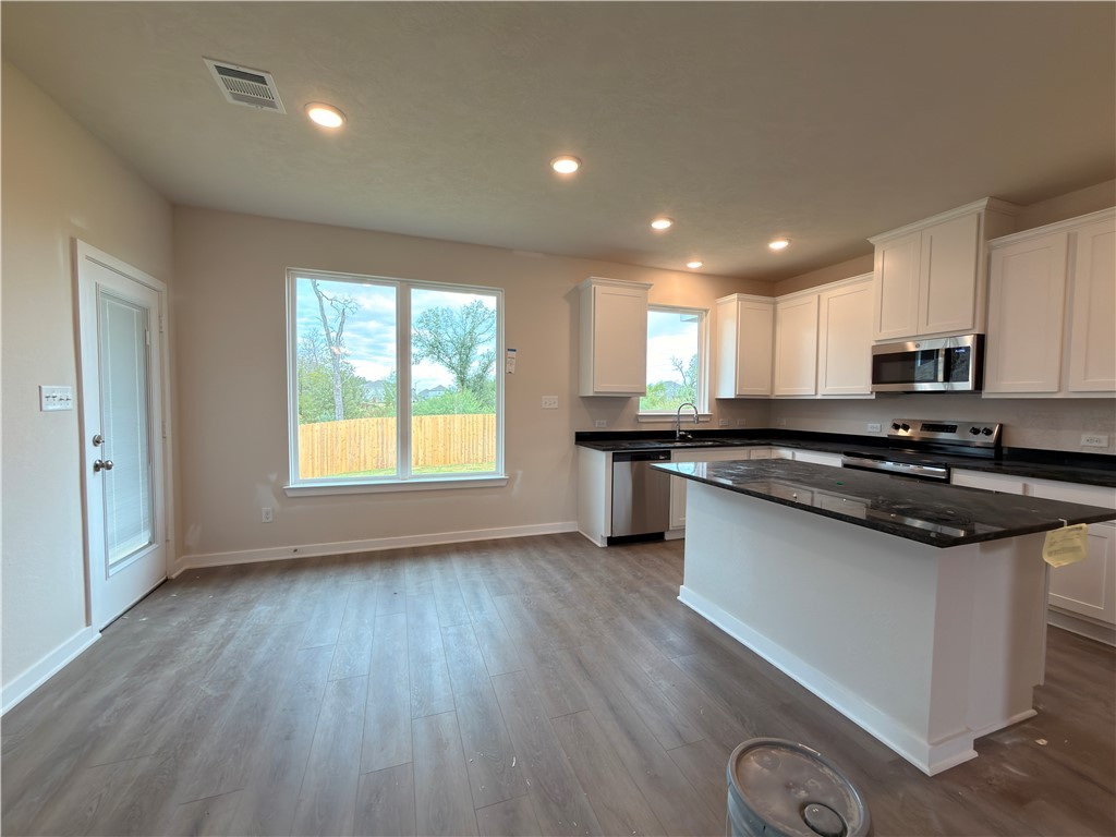 1394 Kingsgate Drive Bryan, TX 77807 - Photo 5 of 10 a kitchen with stainless steel appliances granite countertop hardwood floor sink stove and wooden cabinets