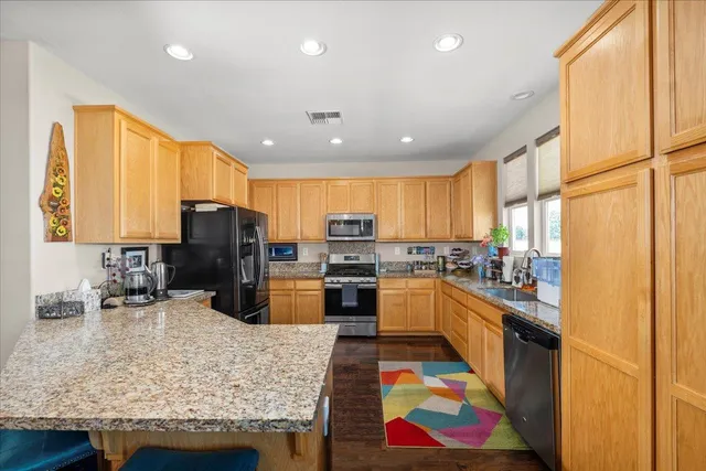 a kitchen with stainless steel appliances granite countertop sink refrigerator and microwave