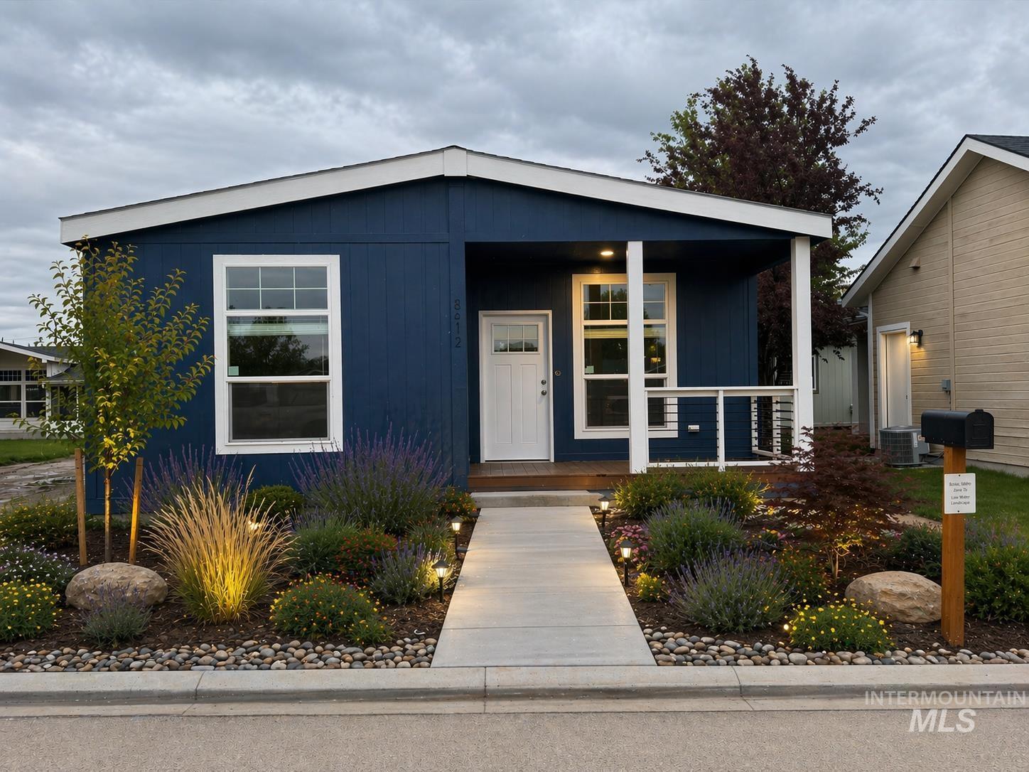 Blue exterior with white trim, featuring a covered porch with white columns and a black metal railing