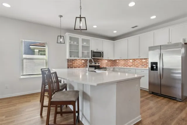 a kitchen with kitchen island a refrigerator and a stove top oven