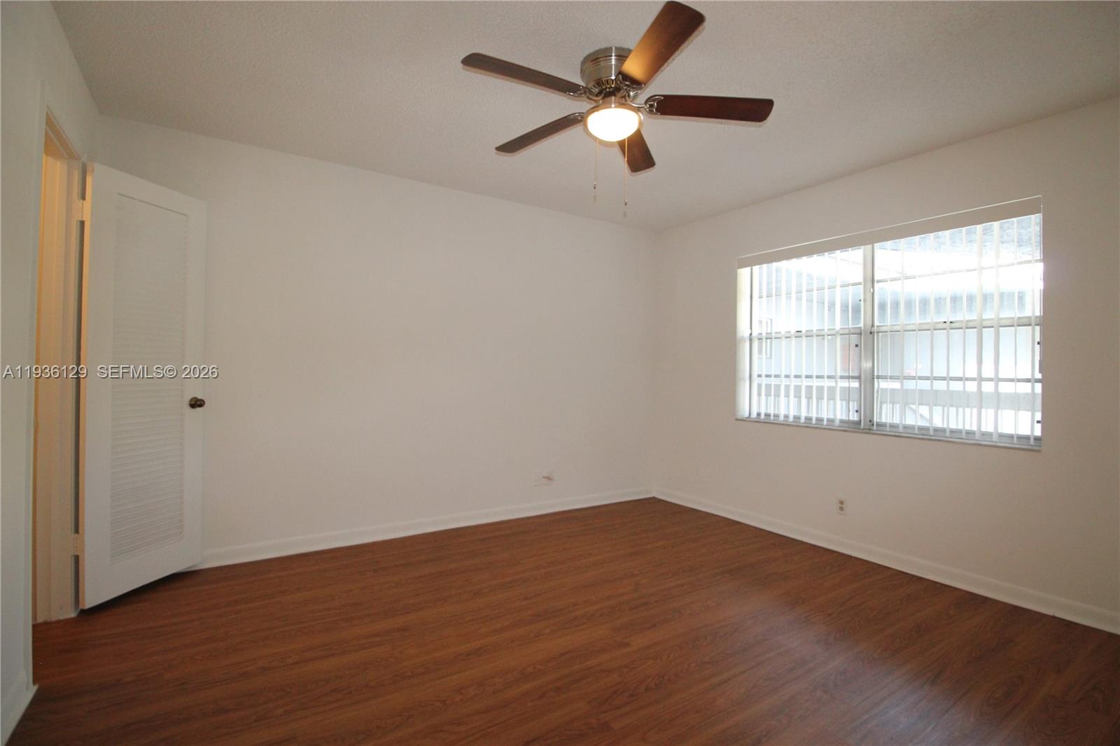 8990 West Sample Road, Unit 206 Coral Springs, FL 33065 - Photo 11 of 28 an empty room with wooden floor fan and windows