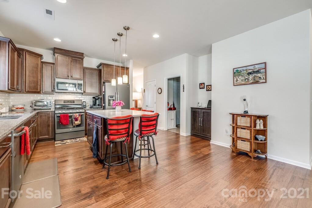 1592 Spring Blossom Trail Fort Mill, SC 29708 - Photo 26 of 36 a kitchen with stainless steel appliances kitchen island granite countertop a table chairs sink and cabinets