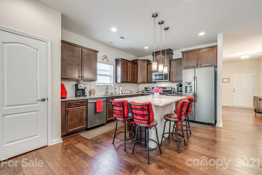1592 Spring Blossom Trail Fort Mill, SC 29708 - Photo 29 of 36 a kitchen with kitchen island granite countertop wooden floors and refrigerator