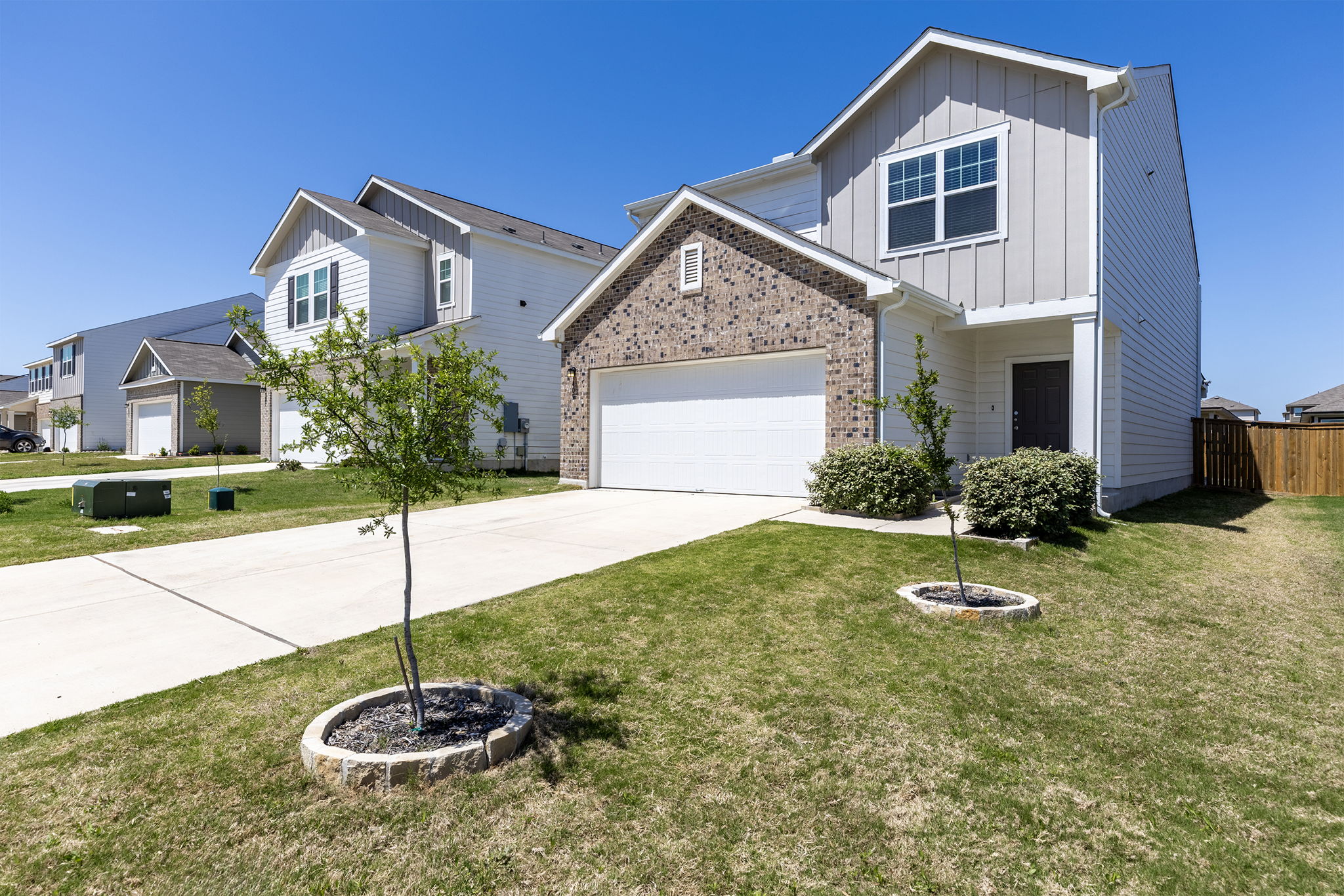 409 Line Of Fire Way Jarrell, TX 76537 - Photo 2 of 30 Two-story residence featuring a brick façade accent, horizontal and vertical siding, attached two-car garage, concrete driveway, covered front entry, and front-facing windows.