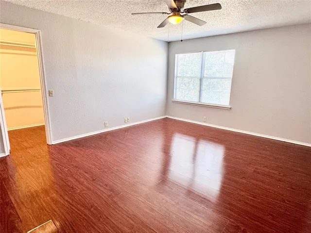 an empty room with wooden floor fan and windows