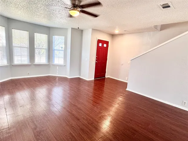 a view of an empty room with window and wooden floor