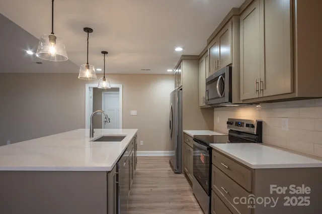 a kitchen with stainless steel appliances granite countertop a sink a stove and a refrigerator