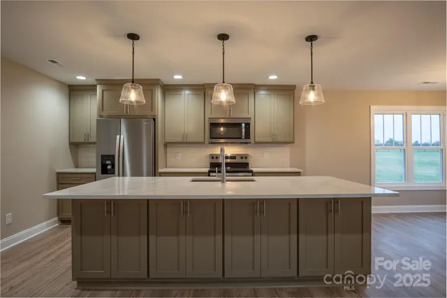 a kitchen with kitchen island granite countertop a sink a center island a stove and a wooden floor