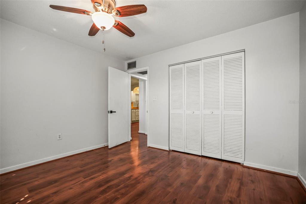 11655 3rd Street East, Unit 19 Treasure Island, FL 33706 - Photo 18 of 48 an empty room with wooden floor chandelier fan and closet area