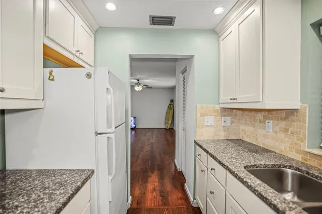a kitchen with granite countertop a sink a stove and cabinets