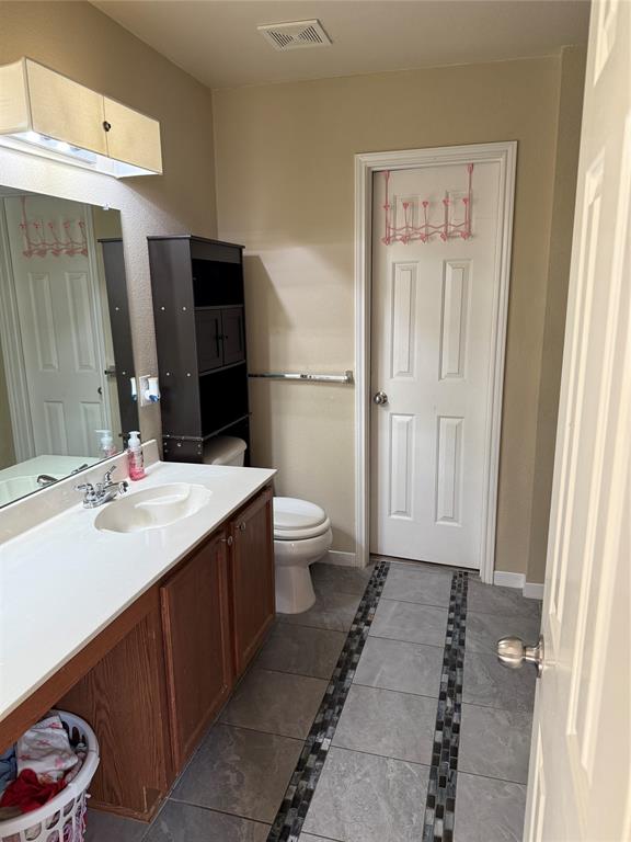 5718 Green Ivy Road Denton, TX 76210 - Photo 11 of 23 Bathroom with inlaid floor details, vanity, and dark tile patterned flooring