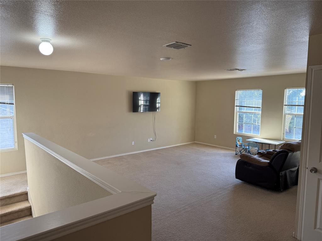 5718 Green Ivy Road Denton, TX 76210 - Photo 13 of 23 Living area with a textured ceiling and carpet flooring