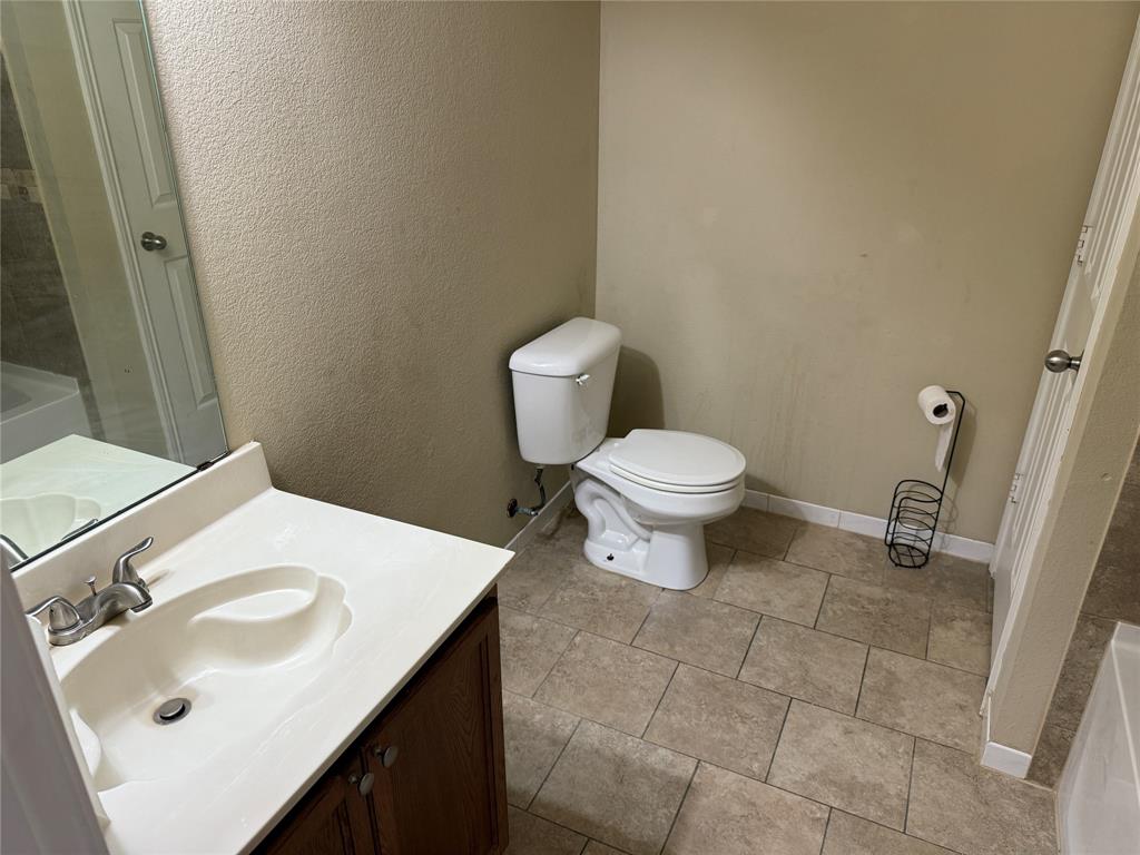 5718 Green Ivy Road Denton, TX 76210 - Photo 15 of 23 Bathroom with a textured wall, vanity, a bath, and light tile patterned floors