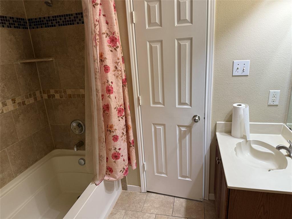 5718 Green Ivy Road Denton, TX 76210 - Photo 16 of 23 Bathroom featuring shower / bath combo, vanity, light tile patterned floors, and a textured wall