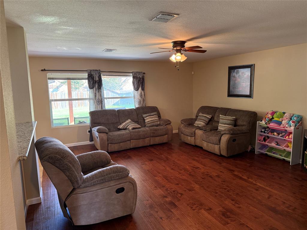 5718 Green Ivy Road Denton, TX 76210 - Photo 4 of 23 Living area with dark wood-type flooring, a ceiling fan, and a textured ceiling