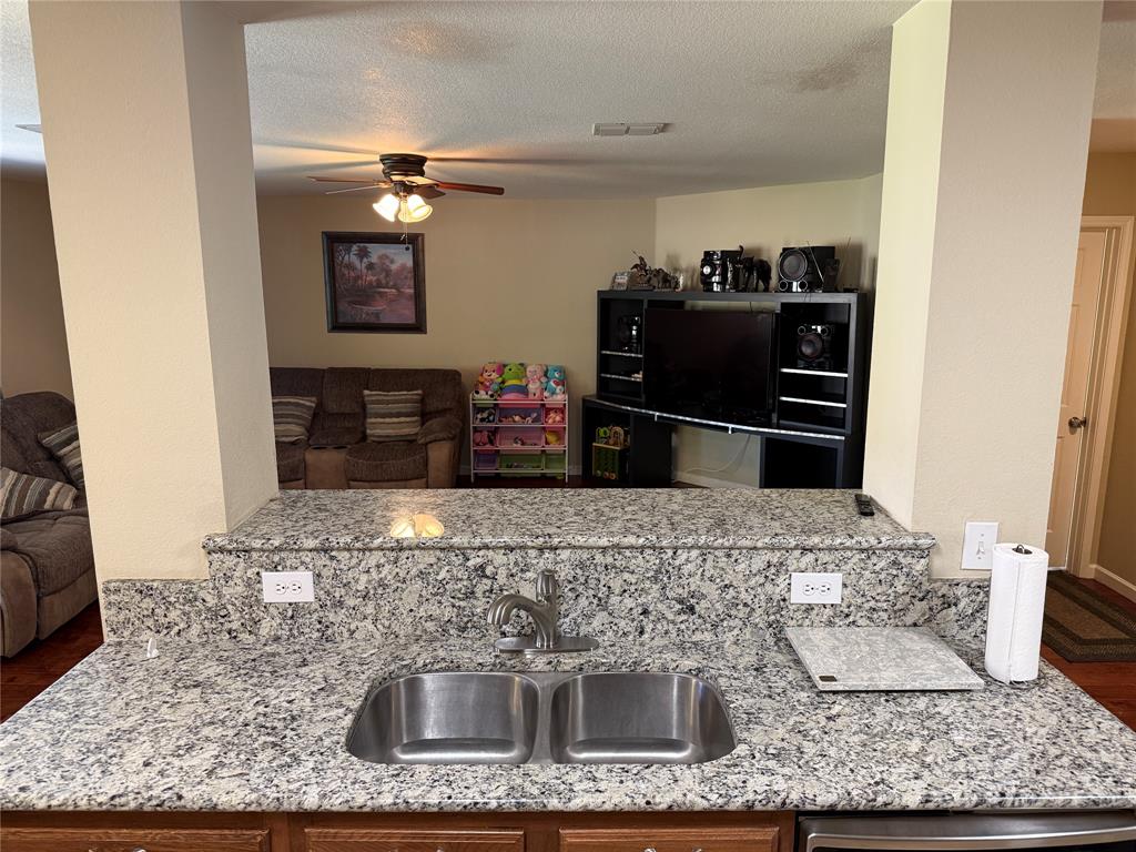 5718 Green Ivy Road Denton, TX 76210 - Photo 23 of 23 Kitchen with ceiling fan, open floor plan, a textured ceiling, and light stone counters