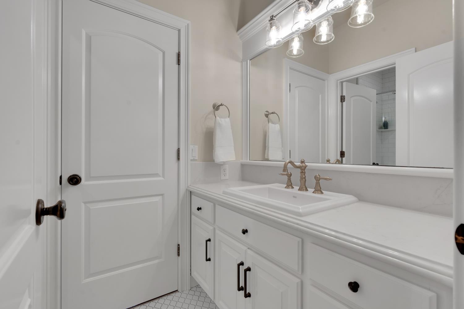 2905 Virginiatown Road Lincoln, CA 95648 - Photo 36 of 86 Main House Upstairs Bathroom vanity featuring an integrated sink with bronze-finish faucet, white cabinetry with dark hardware, and a large mirror. Serves a bedroom and the Media Flex Area