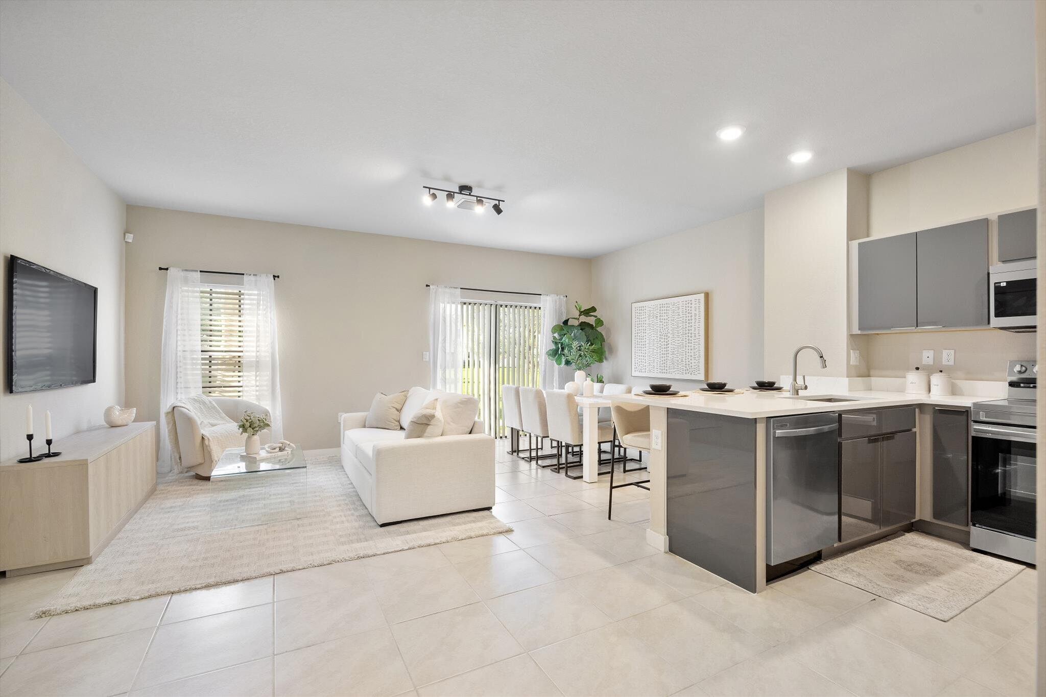 a living room with furniture a flat screen tv and kitchen view