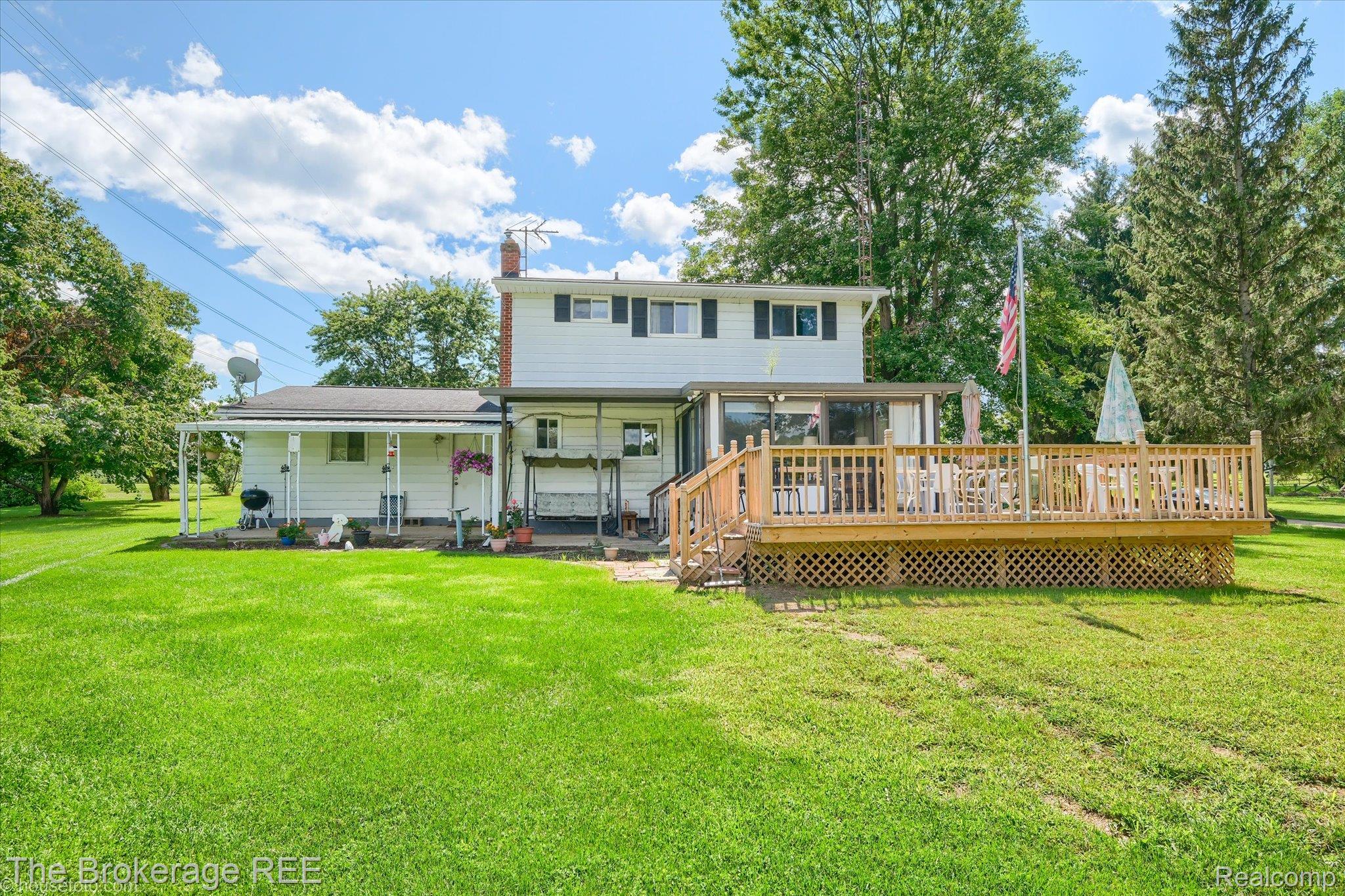 6129 East Lake Road Millington, MI 48746 - Photo 38 of 47 Rear view of house featuring a chimney, a yard, and a deck
