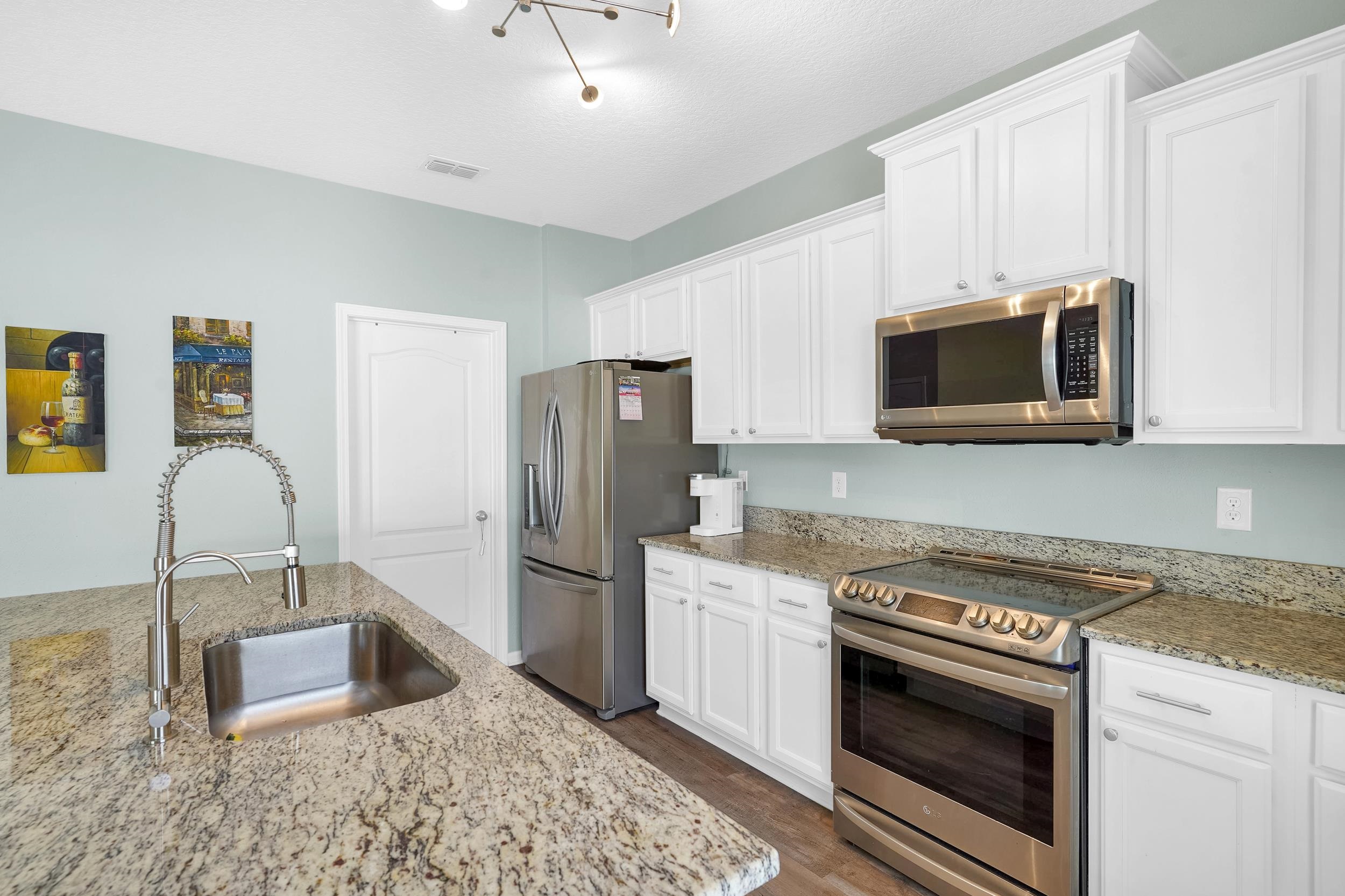 167 Codman Drive St. Augustine, FL 32084 - Photo 13 of 40 Kitchen featuring stainless steel appliances, white cabinets, light stone countertops, and dark wood finished floors