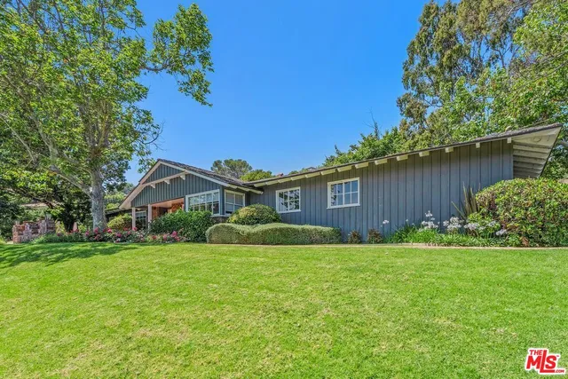 a view of a house with a big yard plants and large trees