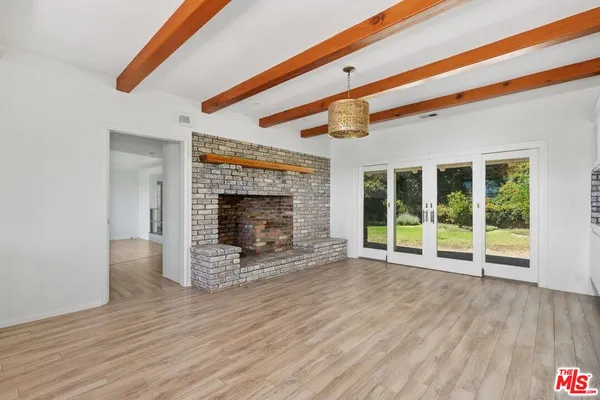 a view of an empty room with wooden floor fireplace and a window