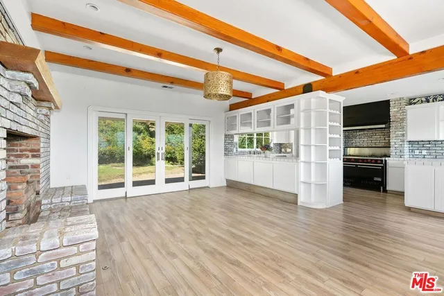 a view of an empty room with kitchen and a window