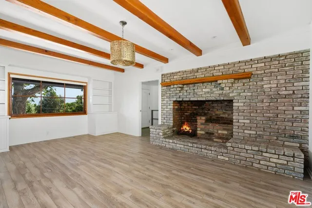 a view of empty room with wooden floor and fireplace