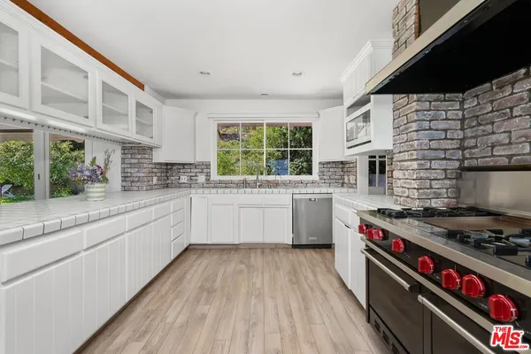 a kitchen with stainless steel appliances a white stove top oven a sink and a large window