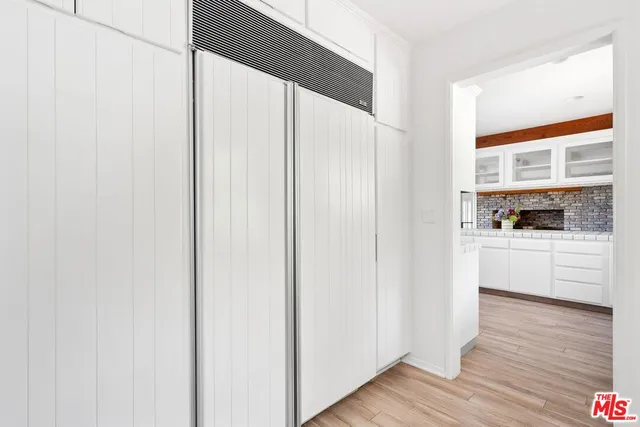 a kitchen with white cabinets and wooden floor