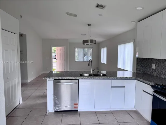 a kitchen with granite countertop a sink and white cabinets
