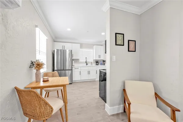 a living room with white furniture and kitchen view