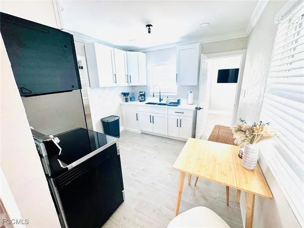 a living room with stainless steel appliances furniture a rug and a window