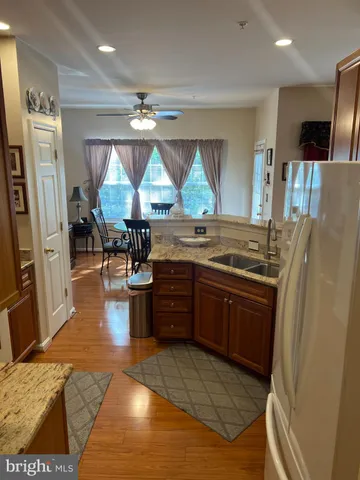 a kitchen with stainless steel appliances granite countertop a refrigerator a sink dishwasher a stove and white countertops with wooden floor