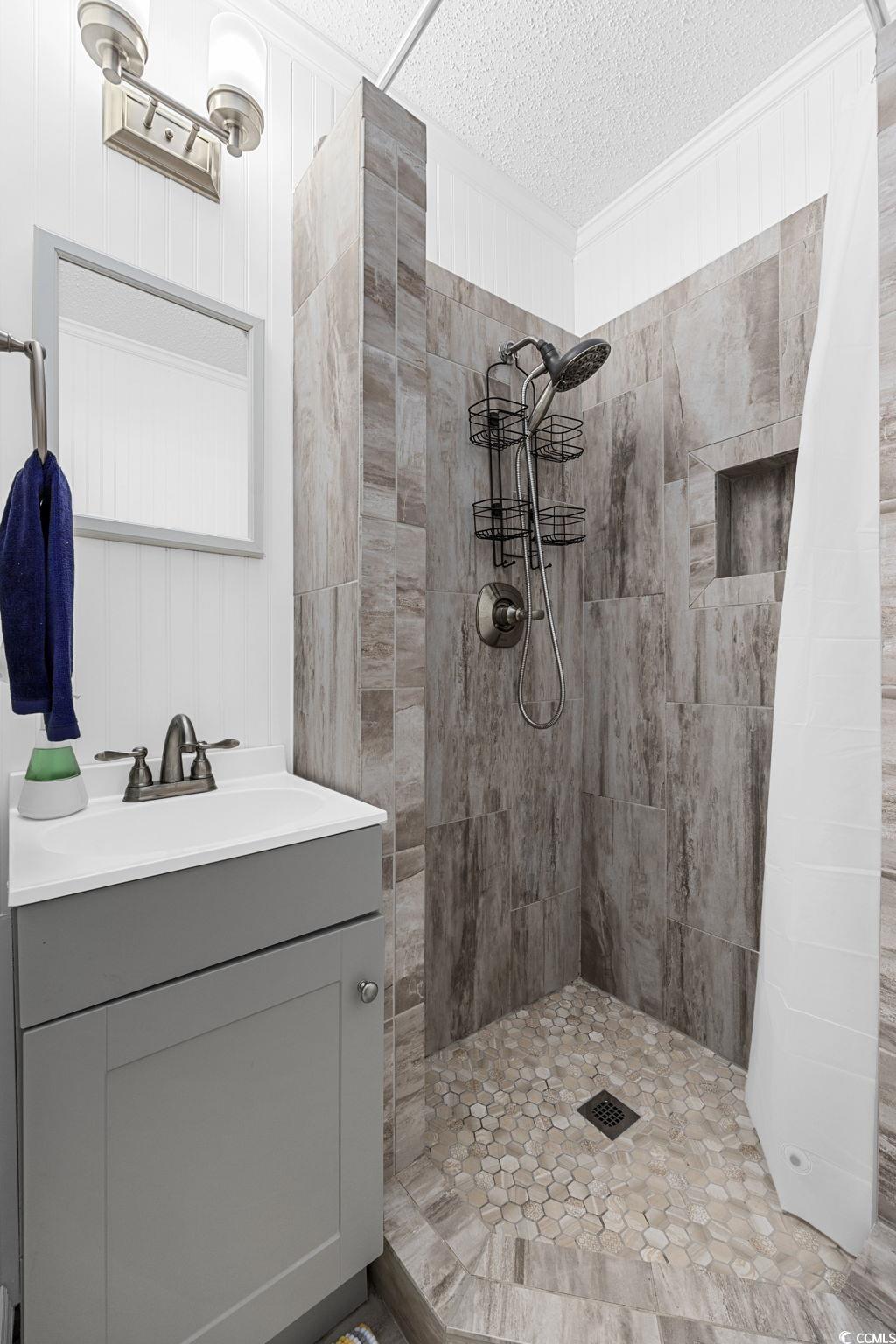191 Maison Drive, Unit B312 Myrtle Beach, SC 29572 - Photo 32 of 40 Full bathroom with tiled shower, vanity, and wooden walls