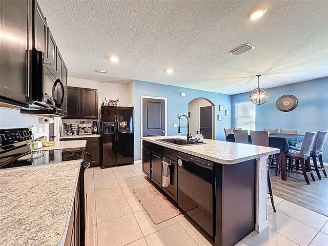 a kitchen with granite countertop a sink a counter top space stainless steel appliances and cabinets