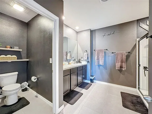 a bathroom with a granite countertop sink a toilet a mirror and shower
