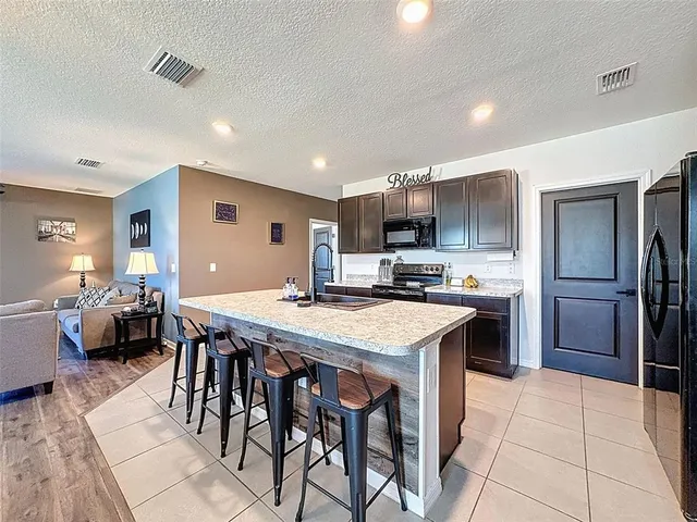 a kitchen with stainless steel appliances granite countertop a stove top oven a sink and a refrigerator